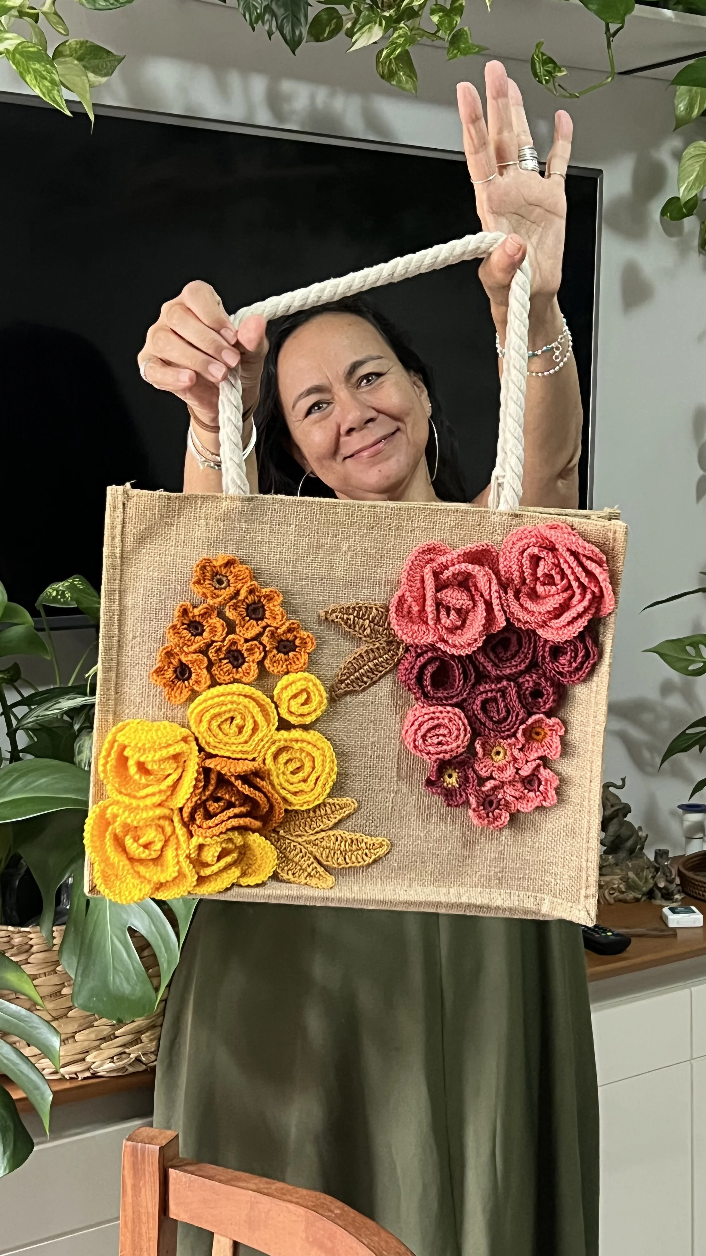 Dra. Sônia Cássia segurando bolsa de juta com flores em crochê