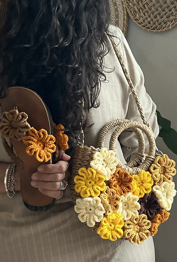 Modelo ao ar livre exibindo a bolsa crossbody de juta florida e calçando os chinelos combinados, estilo editorial de moda
